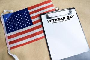 Concept of Veteran Day - Honoring all who served write on paperwork with the united states flag isolated on Wooden Table. photo
