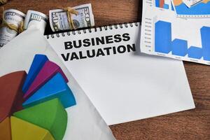 Concept of Business Valuation write on book isolated on Wooden Table. photo