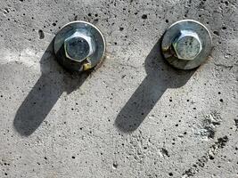 Close up of two bolts and washers fastened to concrete surface. photo