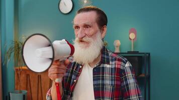 Senior man talking with megaphone announcing news loudly announcing advertising in home office video