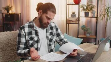 Serious man analyzes contract with a bank at home table clutches head at complex conditions clauses video