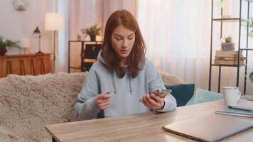 Young Caucasian woman repeatedly plugging and unplugging broken charger into smartphone at table video