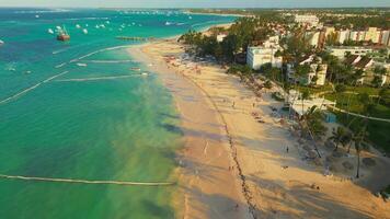 Aerial view of a tropical beach in Punta Cana, Dominican Republic, at sunset. Tourists strolling, relaxing, and swimming in the turquoise ocean, with all-inclusive resorts lining the shore video
