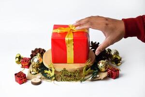 Hand Extending Towards a Red Gift Box with Elegant Gold Script photo