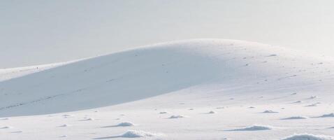A white snow covered hill with a few small snow patches photo