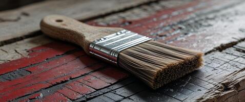 Artisan brush resting on a weathered red and black wooden surface showing strokes and texture photo