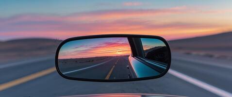 A rear view mirror on a car with a sunset in the background photo