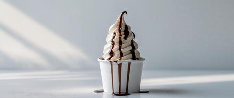 Delicious soft serve ice cream topped with chocolate syrup served in a white cup on a bright surface photo