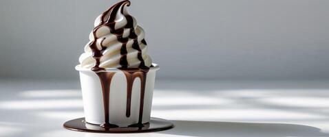 Delicious soft serve ice cream topped with chocolate syrup served in a white cup on a bright surface. photo
