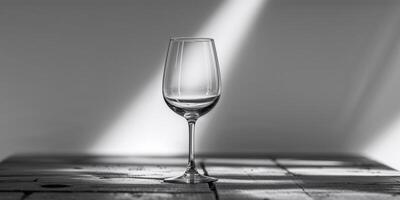 A wine glass is sitting on a table with a shadow of it on the table photo