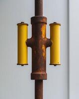 A close up of a rusty pole with two yellow pipes photo