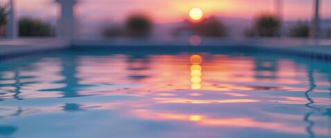 A pool with the sun setting in the background photo
