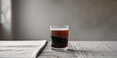 Glass of dark beverage with bubbles on a simple table setting in a studio photo