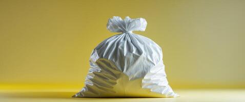 Full white garbage bag tied on a bright yellow background studio shot. photo