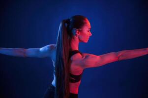 Flexible, body. Beautiful muscular woman is indoors in, the studio with neon lighting photo