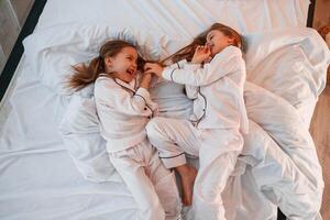 Cheerful and positive two ,little girls are playing and having fun together in bedroom photo