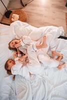Tickling each other, on the bed. Two little girls are playing and having fun together in domestic room photo