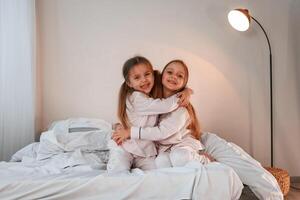 Sisters ,embracing each other. Two little girls are playing and having fun together in domestic room photo