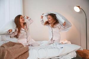 Active ,weekend. On ,the bed with pillows. Two little girls are playing and having fun together in domestic room photo