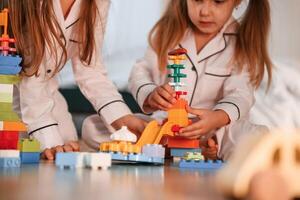 Many of the blocks of plastic construction toys. Two, little girls are playing and having fun together in domestic room photo