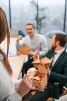 Close up view of meal.. Group of coworkers are eating food from eco boxes in the office together photo