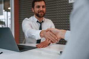 Making handshake, nice to meet you. Office ,workers are indoors by the table photo