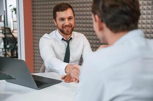 Making, handshake, nice to meet you. Office workers are indoors by the table photo