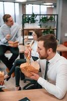 Having a conversation... Group of coworkers are eating food from eco boxes in the office together photo