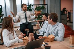 Casual conversation. Group, of coworker,s are eating food from eco boxes in the office together photo