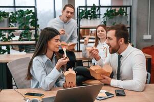 Having a, conversation.. Group of coworkers are eating food from eco boxes in the office together photo
