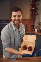 Coffee like look, design of the sweets. Man, is with delicious desserts that are in the eco boxes. Standing indoors photo