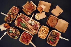 On the black, colored table. Top view of food on it. Meat, vegetables, French fries, burger, mushrooms photo