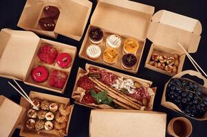 Close up view of table with food on it. Meat, ,vegetables, sushi, French fries, burger, mushrooms photo
