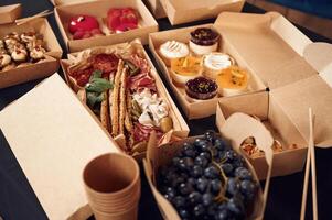 Close up view of table with food on it. Meat, vegetables,, sushi, French fries, burger, mushrooms photo