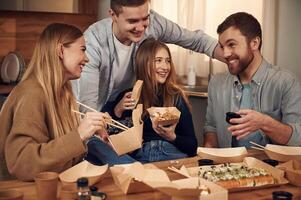 Having fun, casual, conversation. Friends are sitting indoors at home and eating sushi together photo