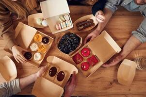 Top view of table with food on it, hands of the people taking it, eating. Macarons, blueberries, desserts, pastry meal photo