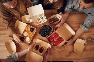 Top view, of table with food on it, hands of the people taking it, eating. Macarons, blueberries, desserts, pastry meal photo
