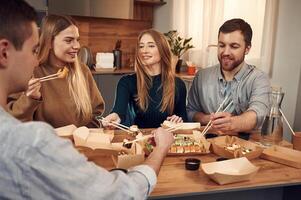 Casual conversation. Friends are sitting indoors at, home and eating sushi together photo