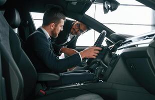 Side view. Man showing automobile, interior to the customer photo