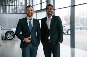 Standing and smiling., Two businessmen are working together in the car showroom photo