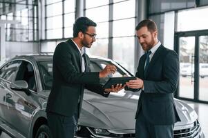 Using, graphic tablet. Man is consulting the customer in the car showroom photo