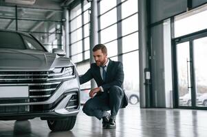 Man in, suit and tie is sitting and checking quality of the vehicle in the car showroom photo