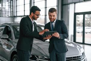 Using graphic tablet. Man is consulting the, customer in the car showroom photo