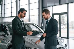 Using graphic tablet. Man is consulting ,the customer in the car showroom photo
