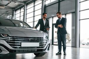 Talking about automobile.. Man is consulting the customer in the car showroom photo