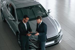 Using graphic ,tablet. Man is consulting the customer in the car showroom photo