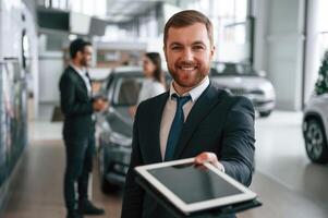 Using ,graphic, tablet. Three people are working together in the car showroom photo