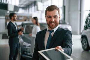 Using graphic tablet. Three ,people are ,working together in the car showroom photo