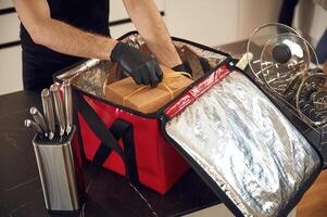 On the table. Man packs ,paper eco boxes into a bag for food delivery photo