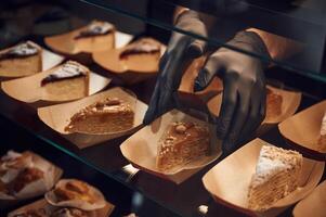 Close up view of man's hands in gloves that taking delicious desserts photo